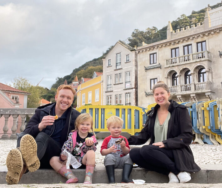 Family eating pastries in Sintra, Portugal with backdrops of historic and colorful buildings