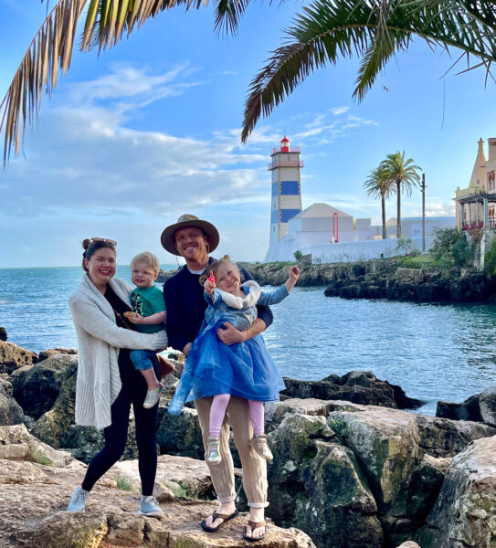 Family with two young kids with picturesque light house and ocean in background in Europe